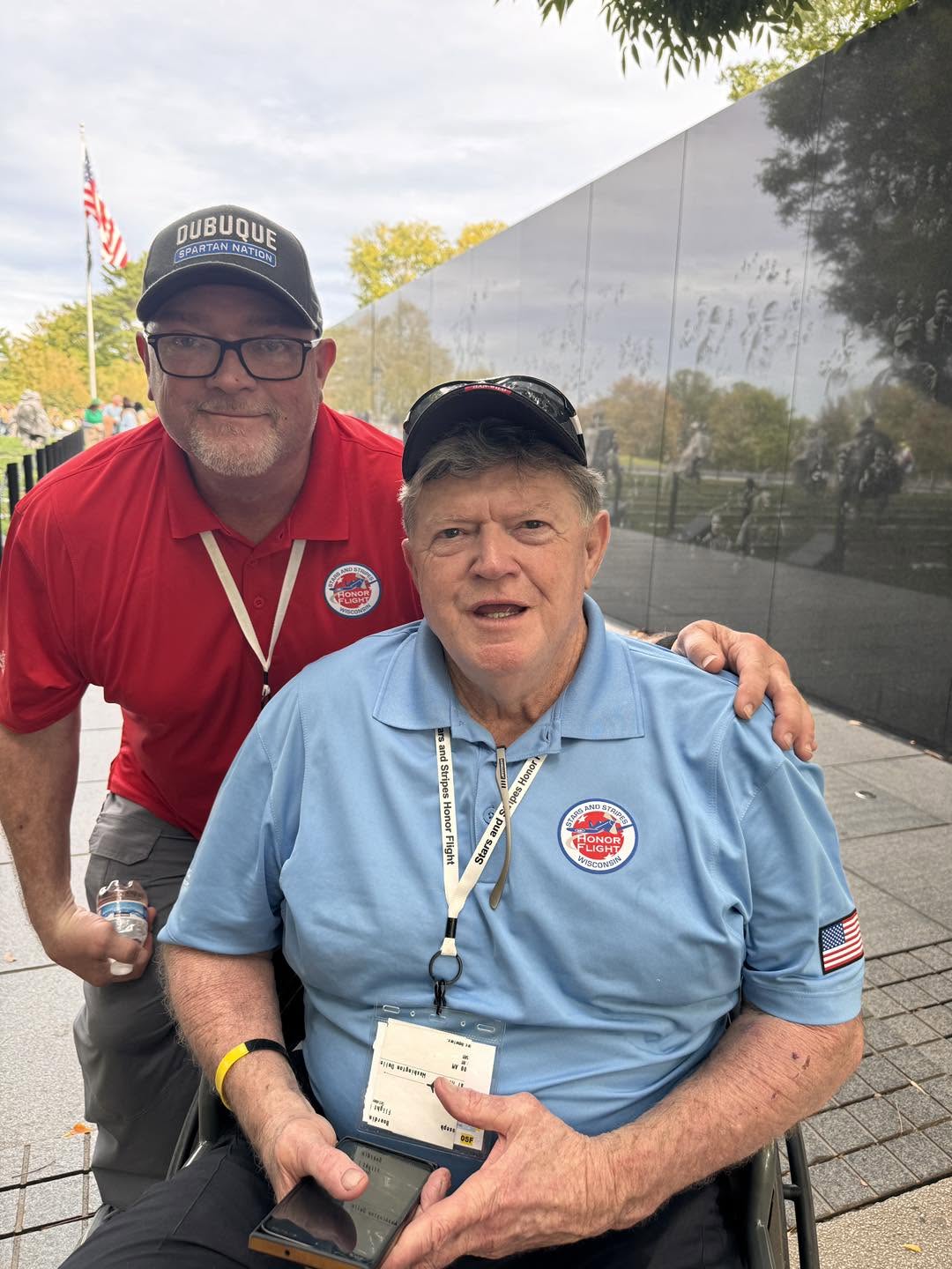 A veteran and guardian beside the Vietnam Veterans Memorial wall.